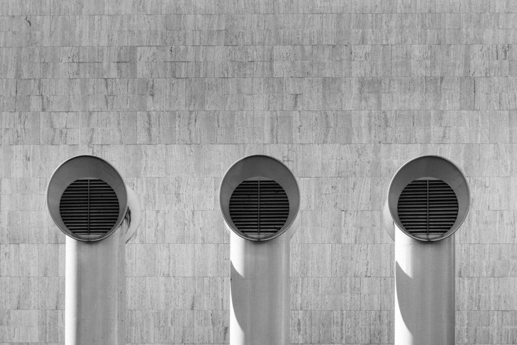 Three ventilation ducts on a building exterior, illustrating the importance of Airflow Sensors in optimizing HVAC systems for energy efficiency.