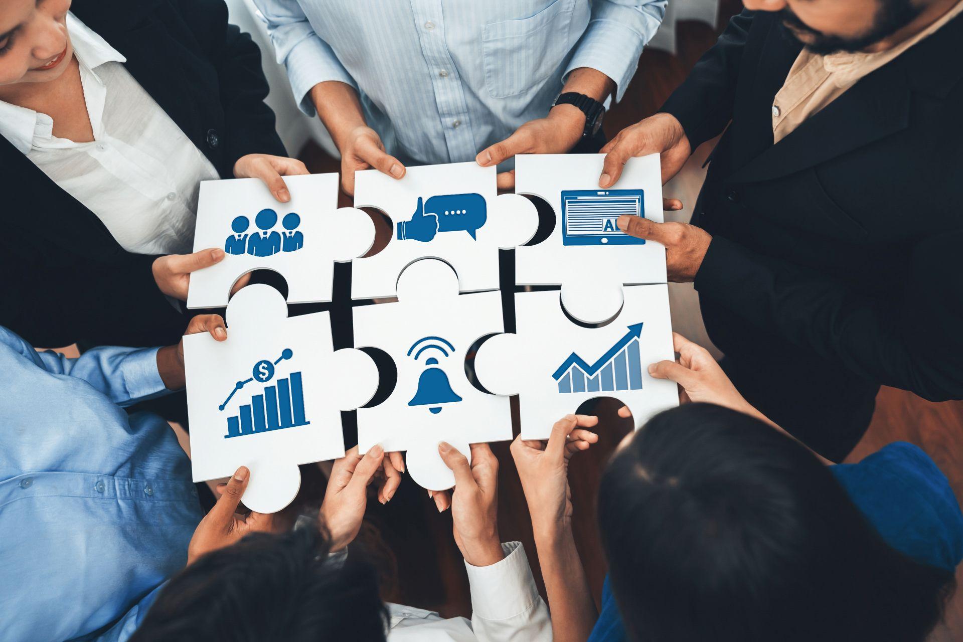 Team assembling puzzle pieces with business icons, representing structured scaling and organizational support provided by only fans managers.